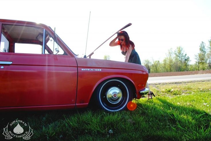 pretty redhead girl checking out datsun 510 engine